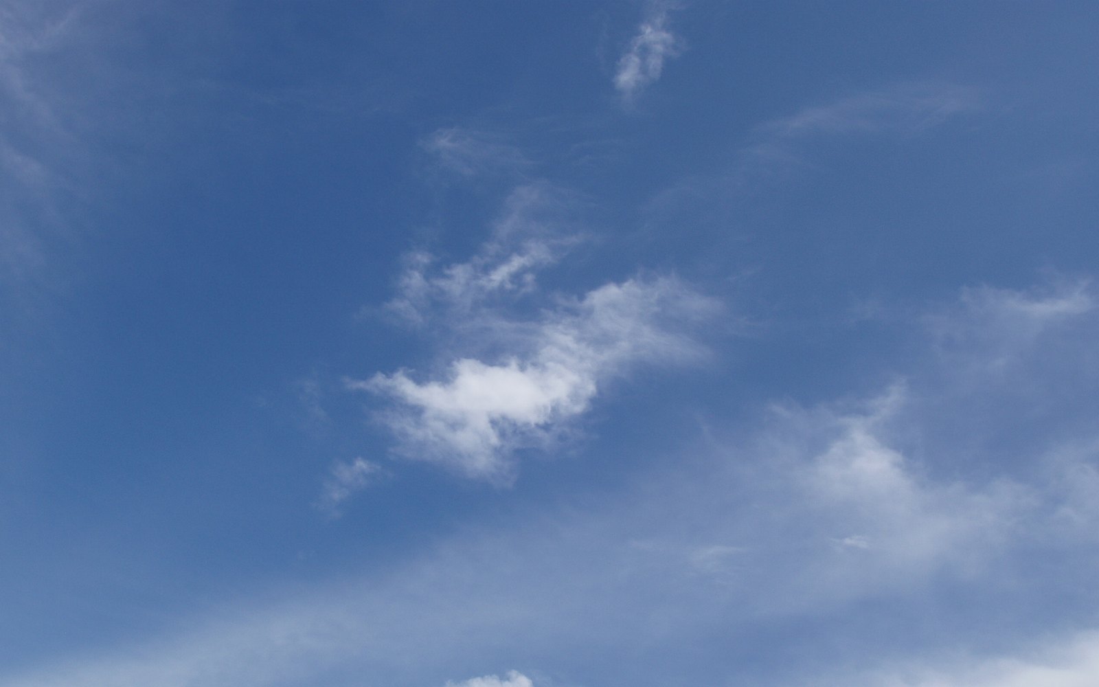 Cielo azul intenso de mediodía con algunas nubes blancas pequeñas y dispersas, sin horizonte ni objetos